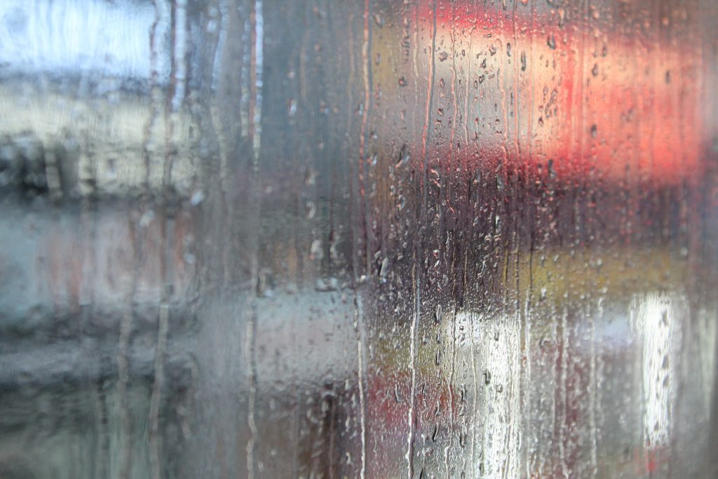 A red light is seen through a rain-covered window